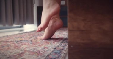 Yakın plan çekim. Yataktan çıkıp pencereye dayanan güzel bir kızın bacakları. Hafif arka plan, sabah uyanır. Beyaz yatak güzel kadın ayak parmakları. Yere yatın. Parke ya da lamine et. fitness bacakları