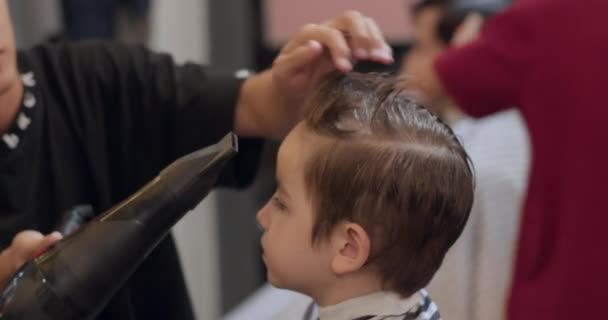 发型师把头发剪短 梳理一下 一个时髦的男孩坐在理发店里 理发师给可爱的小男孩剪头发 迷人的男人在一家现代理发店理发 — 图库视频影像