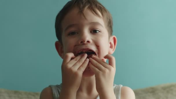 肖像幸せな子供10歳は釉薬で食欲をそそる甘いデザートを食べます 陽気な白人の少女は甘いドーナツを食べる 子供の口の近くに甘いペストリーを食べている — ストック動画