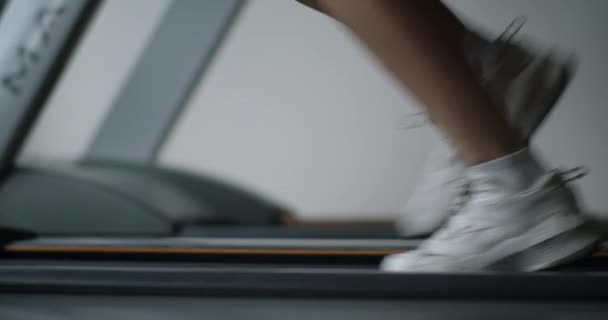 健身女人在健身房的跑步机上跑步 在室内健身馆进行跑步机锻炼 在有氧运动中进行跑步机锻炼时 紧紧围绕女足肌肉 — 图库视频影像