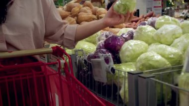 Kadın süpermarketten alışveriş yapıyor, sağlıklı yiyecekler, markette lahana salatası, süpermarket. Market alışverişi konsepti. Süpermarkette yemek pişirmek için ürün seçimi.