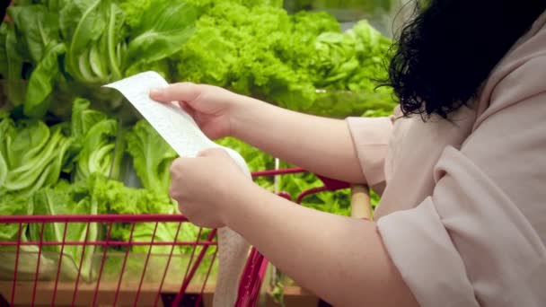 야채의 배경에 여자는 식료품 카트에서 법안을 쇼핑몰에서 식료품에 점검을 합니다 — 비디오