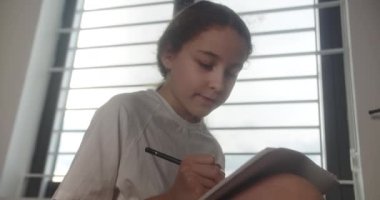 Gülümseyen akıllı küçük kız not defterine yazıyor. Sevimli liseli kız öğrenci evde ders çalışıyor, genç kız odasında otururken yalnız düşüncelerini dile getiriyor..