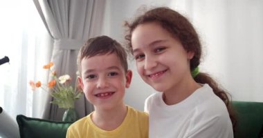 Güzel, gülümseyen bir kız çocuğu. Kameraya bak. Mutlu güzel bir ilişki çocuklar kardeşler küçük erkek ve kız kardeşler, küçük tatlı kız çocuk sarılıyor, tatlı şefkatli sevginin tadını çıkarıyor.
