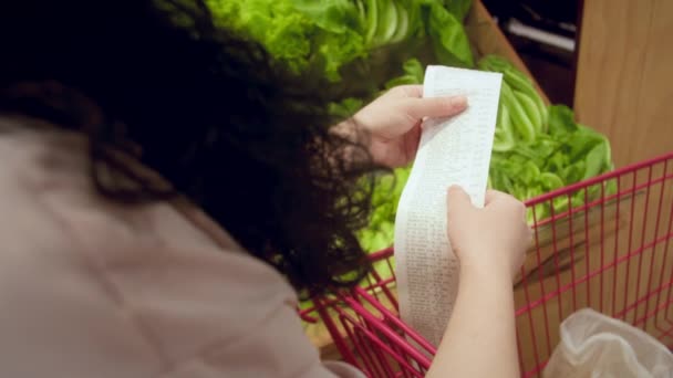 Vrouw Tegen Achtergrond Van Groenten Controleert Papier Controleren Het Winkelen — Stockvideo