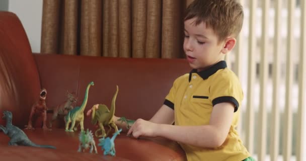 Anak Yang Lucu Berbicara Dengan Mainan Mainan Dinosaurus Duduk Atas — Stok Video