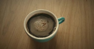 Adding coffee creamer into black coffee. Slow motion cream pouring in a cup of black coffee
