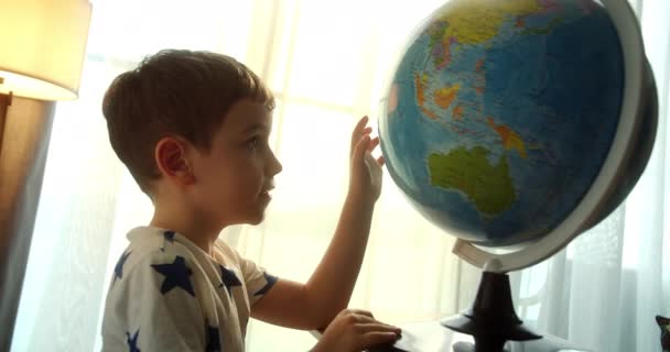 Dziecko Trzyma Szkło Powiększające Rękach Patrzy Kulę Ziemską Siedząc Domu — Wideo stockowe