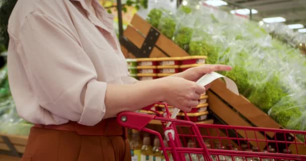 Kvinna Mot Bakgrund Grönsaker Kontrollerar Papper Kontroll Efter Shopping För — Stockvideo