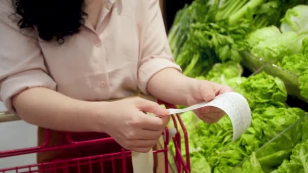 가격에 식료품점 손수레를 검사하는 야채의 배경에 여자는 쇼핑몰에서 식료품에 점검을 — 비디오