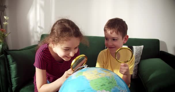 Dzieci Trzymają Szkło Powiększające Jego Rękach Patrzą Glob Siedząc Domu — Wideo stockowe