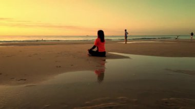 Güzel ve özgür Asyalı kadın meditasyonda otururken günbatımında Vietnam plajında poz veriyor. Nilüfer pozisyonu, yoga, yoga, kundalini enerjisini dengelemek. Her gün rutin uygulama, kadınların sağlık bilincine iyi geliyor.