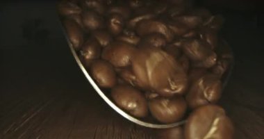 Taze kavrulmuş kahve çekirdeği kavramı, lezzetli, aromatik, kavrulmuş birinci sınıf Arabika fasulyesi. Kızarmış kahve çekirdekleri spatuladan ahşap bir masaya dökülüyor. 4K