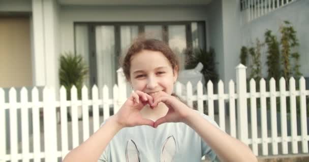 행복한 여학생 즐거운 미소를 카메라를보고 그녀의 손가락을 연동하여 상징을 저녁에 — 비디오