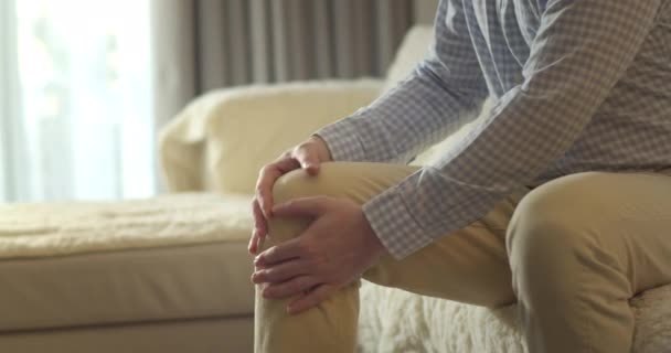 Fecha Mãos Masculinas Massajando Músculos Perna Joelho Enquanto Sentado Sofá — Vídeo de Stock