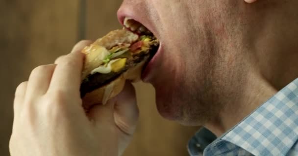 Крупным Планом Рот Голодного Человека Брекетами Зубах Жадно Кусает Гамбургер — стоковое видео