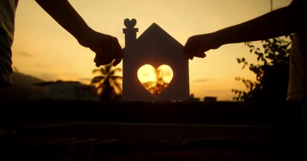 Familjens Händer Håller Ett Pappershus Vid Solnedgången Solen Skiner Genom — Stockvideo