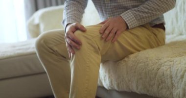 Kapatın. Erkek eller, evdeki oturma odasında kanepede otururken diz kaslarına masaj yapıyor. Yaşlı siyahi adam diz eklem ağrısı çekiyor, yürüyemiyor, hastalık, kramp, romatizma.
