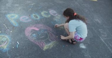 Sevimli küçük çocuk asfalta tebeşirle barış çiziyor. Küçük çocuğun tebeşirle barış yazması. Savaşı protesto etmek, Rusya 'nın Ukrayna' yı işgal etmesi. 4K.