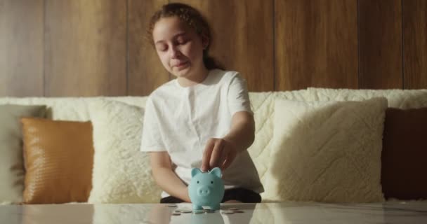 一个心烦意乱 泪流满面的人把他的钱记在储蓄罐里 小孩把硬币扔进了储蓄罐 小猪银行里的硬币象征着银行的安全 财政储蓄 经济保障中的儿童 — 图库视频影像