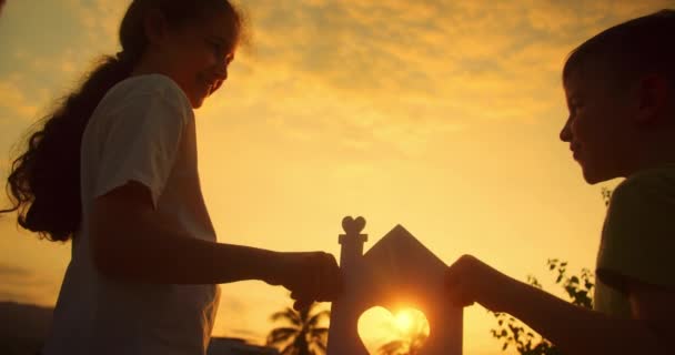 Kinder Mit Ihren Eigenen Händen Halten Bei Sonnenuntergang Ein Papierhaus — Stockvideo