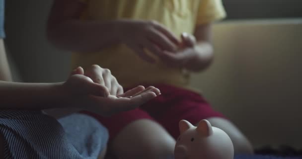 孩子们把硬币扔进粉红猪储蓄罐 小猪银行里的硬币象征着银行的安全 财政储蓄存于银行 儿童为商业和财政安全作准备的概念 — 图库视频影像