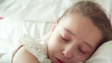 Yanaklarından büyük yaşlar süzülen küçük bir kızın portresi, çocuk evde annesinin yanında yatıyor ve ağlıyor, gözyaşları çığlık çığlığa akıyor..