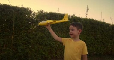 Çocuk pilot ve astronot olmak istiyor. Ağır çekim. Mutlu çocuk, gün batımında parkta oyuncak bir uçakla koşuyor. Çocuklar oyuncak uçak oynarlar. Gençler uçmayı ve pilot olmayı hayal eder. 4K