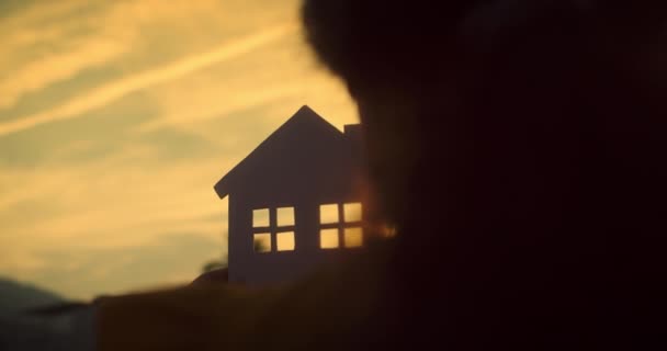 Paperi Käsissä Perhe Aurinko Paistaa Ikkunan Lähikuva Kädet Paperitalo Auringonlaskun — kuvapankkivideo
