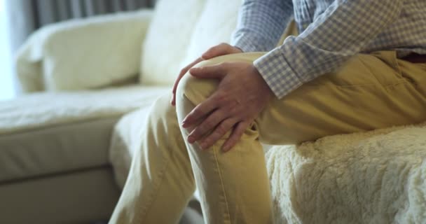 クローズアップ 男性の手は 自宅のリビングルームでソファーに座っている間 膝の筋肉をマッサージします シニア黒人男性は痛みを伴うひざ関節痛に苦しみ 歩くことができず クランプ リウマチ — ストック動画