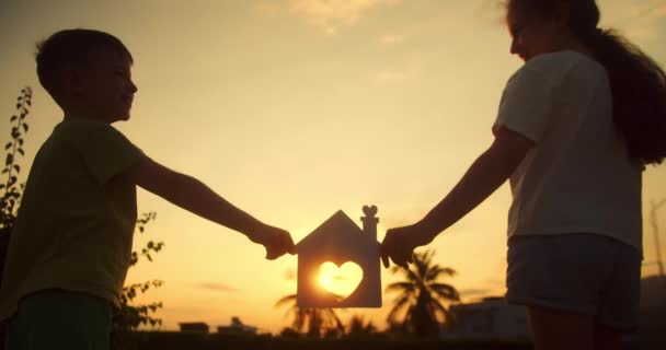 Kinder Mit Ihren Eigenen Händen Halten Bei Sonnenuntergang Ein Papierhaus — Stockvideo