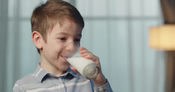 かわいい子供はミルクを飲む 子供が朝食を食べる健康的な子供の夢のコンセプト キッチンの息子の小さな男の子はヨーグルトミルクを飲み 彼女の唇を舐めます — ストック動画