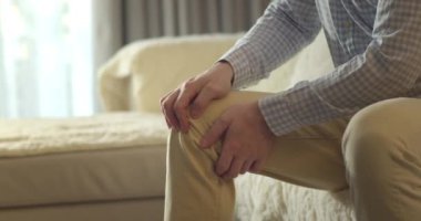 Kapatın. Erkek eller, evdeki oturma odasında kanepede otururken diz kaslarına masaj yapıyor. Yaşlı siyahi adam diz eklem ağrısı çekiyor, yürüyemiyor, hastalık, kramp, romatizma.