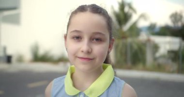 Küçük Çocuk Kız 'ın Yaz Günü' nde Cadde 'de duran kameraya baktığı portre. Genç Mutlu Düşünen Meraklı Çocuk Dışarıda Kameraya Yakından Bakıyor. Yüz Gözleri Komik Düşünceli Çocuk. 4K