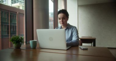 Ofisteki modern dizüstü bilgisayarda daktilo yazan odaklı iş kadını. Yakın plan. Gözlüklü çekici genç kız yönetici bilgisayar ekranlı oturma masasında oturuyor. İnternette sörf yapan ciddi kadın şirket çalışanı.