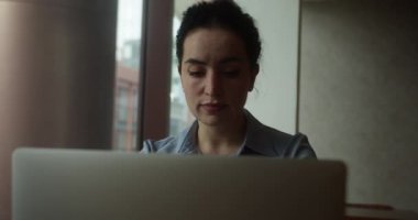 Ofisteki modern dizüstü bilgisayarda daktilo yazan odaklı iş kadını. Yakın plan. Gözlüklü çekici genç kız yönetici bilgisayar ekranlı oturma masasında oturuyor. İnternette sörf yapan ciddi kadın şirket çalışanı.