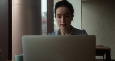 Ofisteki modern dizüstü bilgisayarda daktilo yazan odaklı iş kadını. Yakın plan. Gözlüklü çekici genç kız yönetici bilgisayar ekranlı oturma masasında oturuyor. İnternette sörf yapan ciddi kadın şirket çalışanı.