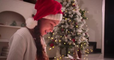 Noel hediyesi kutusunu açan yakışıklı ve şaşkın çocuk şöminenin yanındaki geleneksel oturma odasında oturuyor. Portre küçük çocuk, mutlu sürpriz çocuk