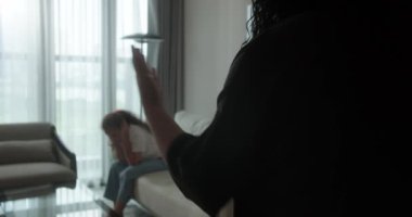 Aile içi şiddet: Bir anne, kanepede oturan ve başını tutup gözlerini korkuyla kapatan çocuğuna doğru elini kaldırır. Anne öfkeyle genç kızına bağırıyor.