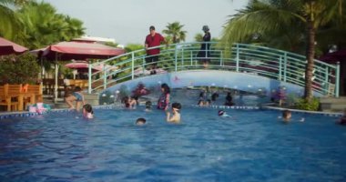 Çocuklar havuzda yüzüyorlar. Nha Trang, Vietnam - 31 Ağustos 2024: Çocuklar yüzme havuzunda yüzme tahtasıyla yüzmeyi öğreniyorlar. Yüzme tekniği. Mayo: şapkalar, mayolar ve gözlükler. eğitim.