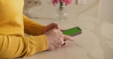 Akıllı telefon kullanıcısı ev masasında yeşil ekran görüntüsünü kapatıyor. Elinde krom bir cep telefonu olan tanınmayan bir kadın mesaj yazıyor. Sabahları cep telefonundan e-postaları kontrol eden kadın