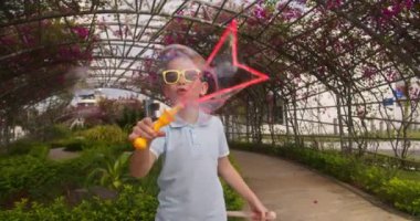 Joy Kid yaz günü sabun köpüğüyle oynuyor. Yeşil ağaçların arka planına sabun köpüğü üfleyen mutlu çocuk. Küçük çocuk doğada dinleniyor. Aile hafta sonu kavramı. Tatil sabun köpükleri