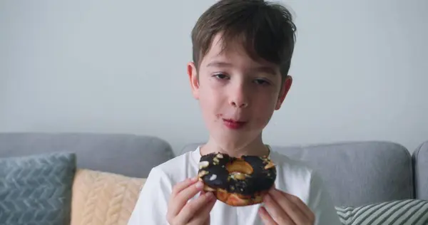 Mutlu bir çocuğun portresi iştah açıcı tatlı bir çöreği jöleli yiyor. Neşeli beyaz bir kız tatlı bir çöreğin tadını çıkarıyor. O tatlı pastayı yerken, çocuğun ağzına yakın çekim yap..