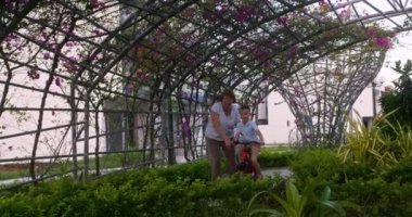 Büyükannesi torunuyla birlikte bisiklete biniyor. Büyükanne torununa iki tekerlekli bisiklet sürmeyi öğretiyor. 7 yaşındaki mutlu torun büyükannesiyle birlikte parkta bisiklet sürüyor.