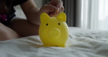 Kumbaradaki bozukluklar bankanın güvenlik sembolü. Çocuk kumbarada para biriktiriyor. Yakın plan. Yakından kumbaraya bozuk para atıyorlar. Mali güvencedeki çocuklar. Finansal tasarruflar.