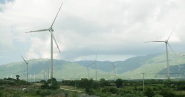 Alternatif enerji. Hava manzaralı siluetler yel değirmenleri, büyük turuncu güneş diski yaz merceği parlamaları. Vietnam. Parlak turuncu renkli parlak mavi gökyüzü güneşli büyük rüzgar türbini kapatın. 4K.