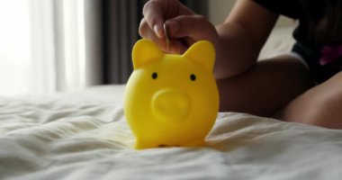 Kumbaradaki bozukluklar bankanın güvenlik sembolü. Çocuk kumbarada para biriktiriyor. Yakın plan. Yakından kumbaraya bozuk para atıyorlar. Mali güvencedeki çocuklar. Finansal tasarruflar.