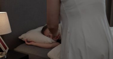 Anne oğluna bakıyor. Yatakta uyuyan bebek. Yan yatmış uyuyan çocukla yüzleş. İzleme, gece yarısı uyuyan bebeği vurdu. Küçük erkek bebek beşiğinde tatlı tatlı uyuyor ve uykusunda gülümsüyor.