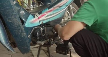 Yetenekli bir kadın tamirci bir atölyede bir motosikleti tamir eder. Hanoi, Vietnam 'da, kendi dükkanında motosikletler üzerinde çalışıyor, üst düzey bir oto tamircisi olarak uzmanlığını gösteriyor.