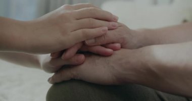 Yaşlı anne ve torun nazikçe el ele tutuşup sarılıyorlar. Yaşlı annesiyle el ele tutuşan bir torun. Yaşlı bir anne ve torununun elleri. 4K